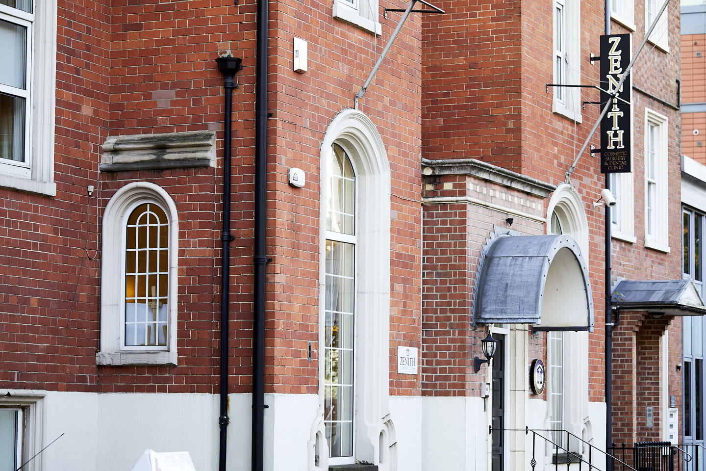 Red brick exterior of Zenith Cosmetic Surgery and Dental Clinic with arched windows and canopied entrance