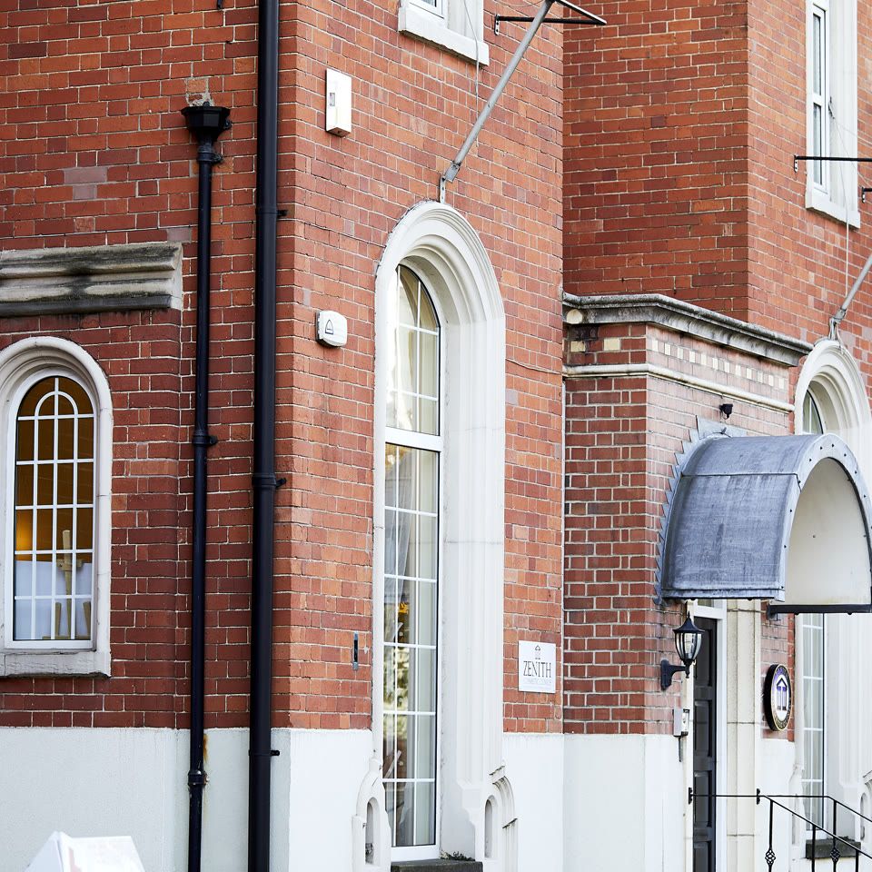 Exterior of Zenith Cosmetic Surgery and Dental Clinic, a red brick building with arched windows and canopied entrance