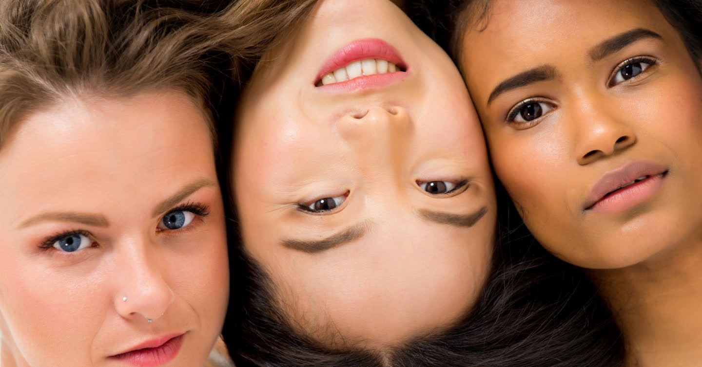 Three women with diverse skin tones resting their faces close together, showcasing smooth radiant skin