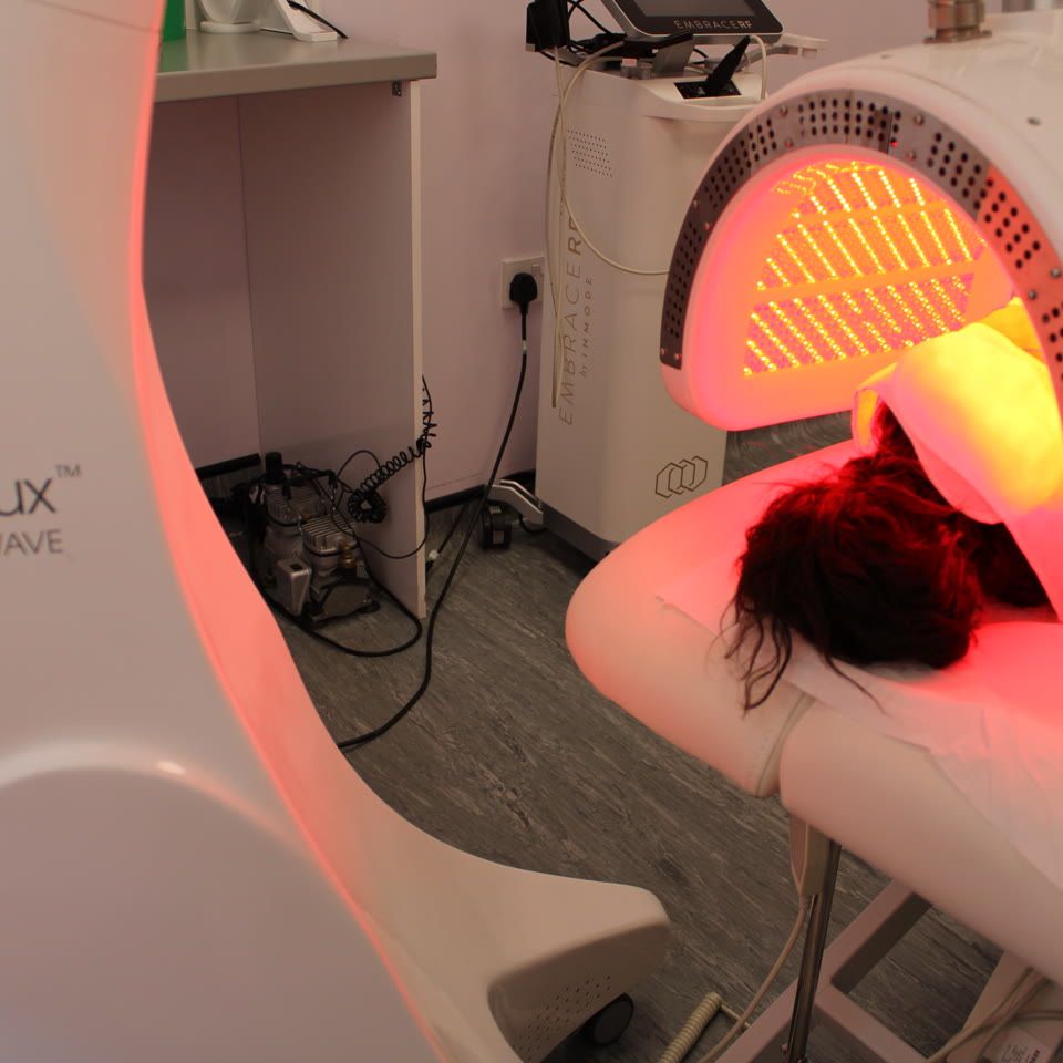Client receiving Dermalux TriWave LED light therapy treatment with red light in a clinical treatment room